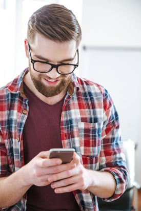 Closeup of smiling handsome bearded man in checkered shirt using mobile phone.jpeg