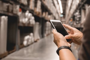 man holding his smartphone in a manufacturing facility