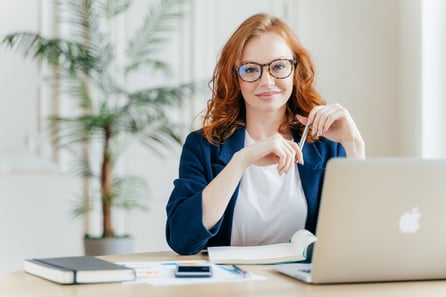 woman in an office smiling from her desk